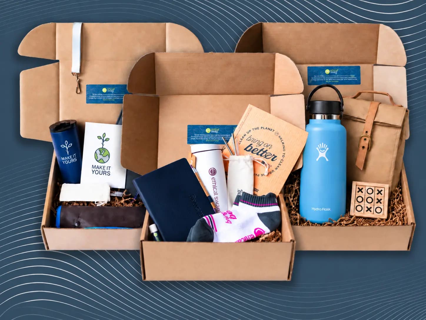 Open swag pack boxes with a water bottle, notebook, socks, and other branded products