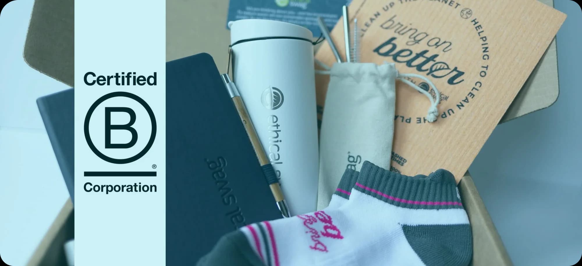 Assortment of Ethical Swag products including a B Corp certified notebook, tumbler, and reusable straws, demonstrating a commitment to sustainability and ethical practices.