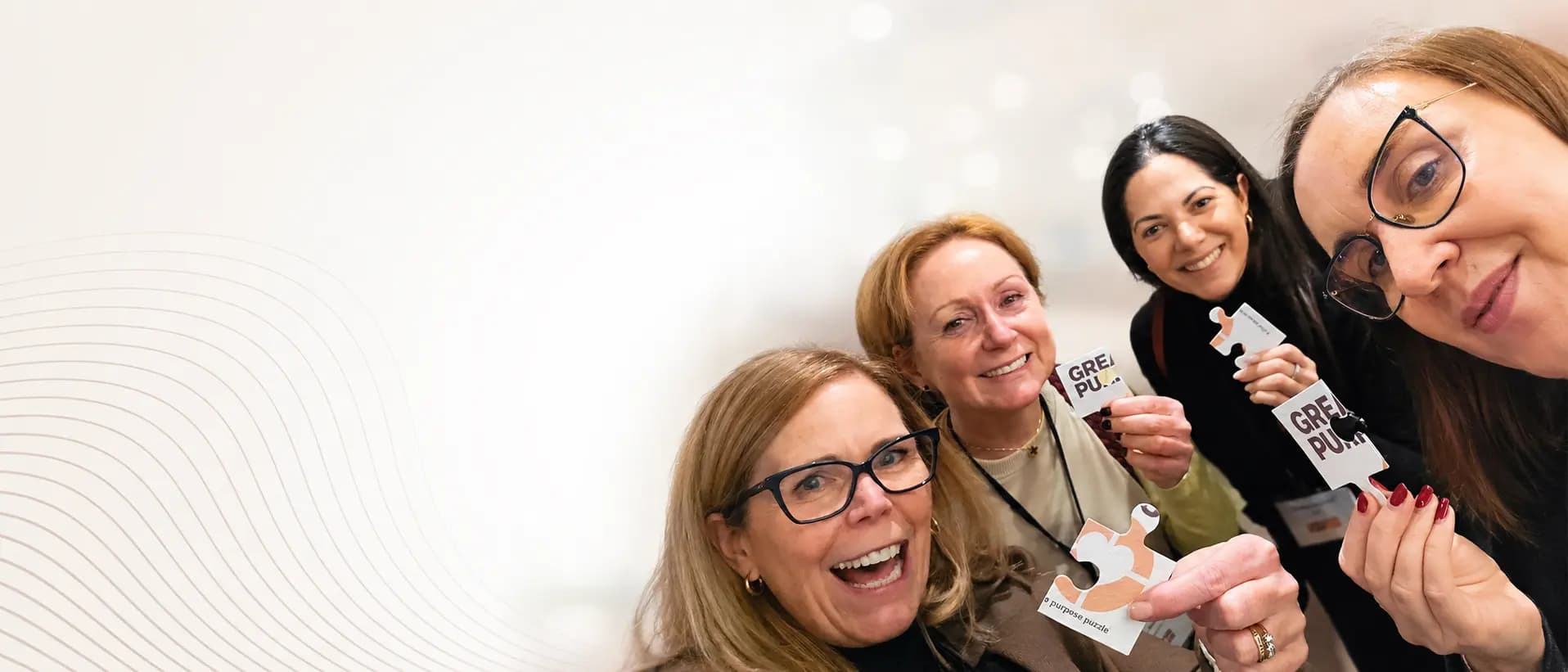 Four attendees smiling at a Greater Purpose networking event, each holding a piece of a branded purpose puzzle icebreaker card