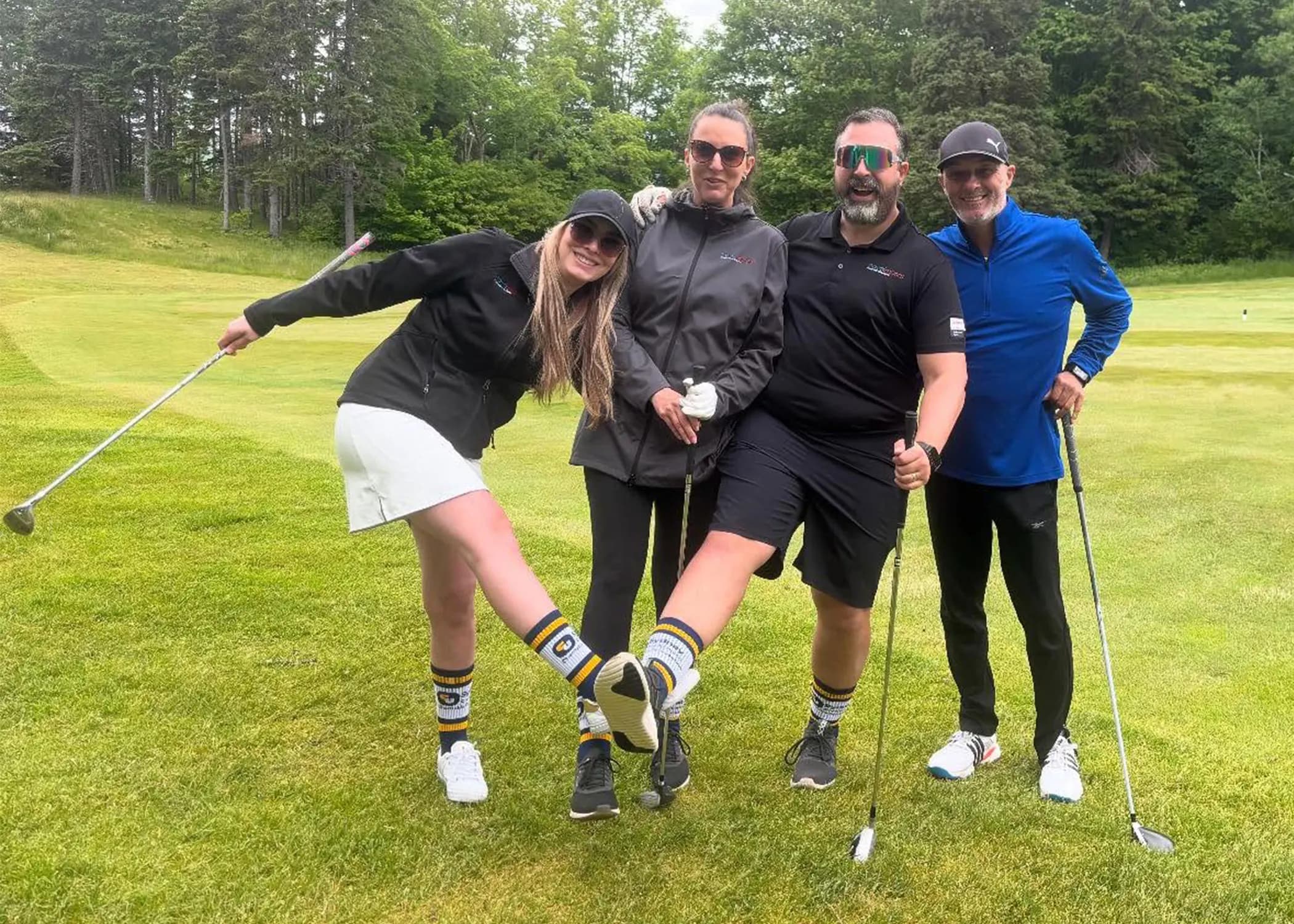 Four Sydney Credit Union tournament participants lifting a leg on the course to show off their branded knee-high socks