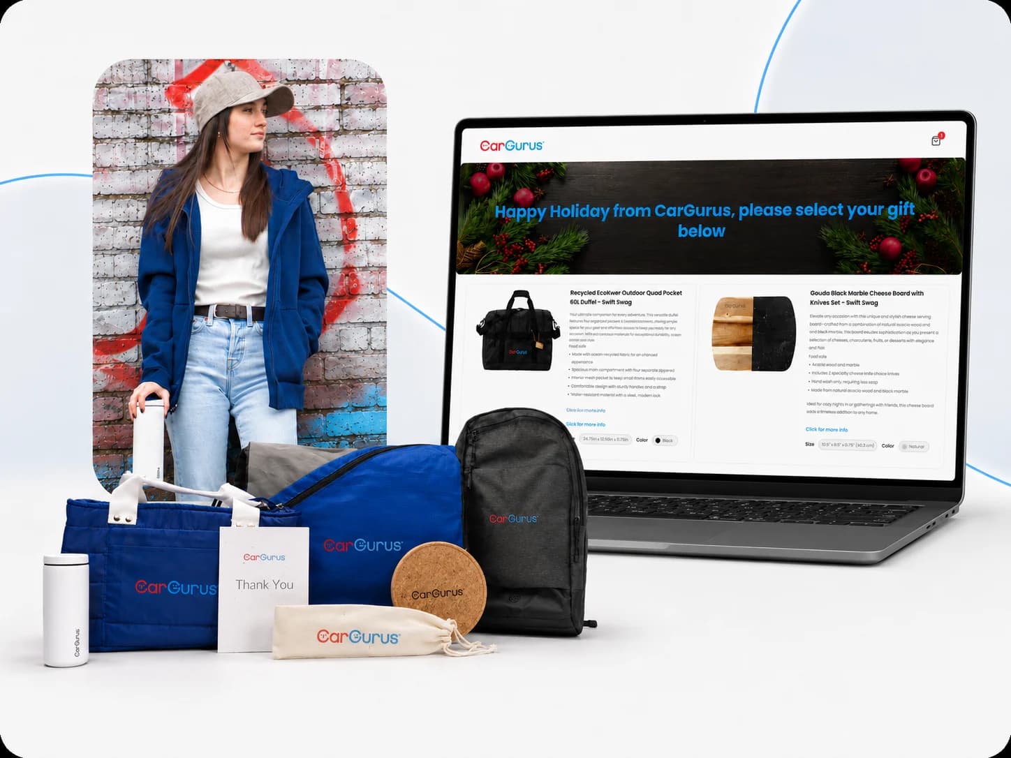 A model wearing a CarGurus-branded hoodie next to a laptop showing the CarGurus gift-selection page, surrounded by branded duffel bags, a backpack, and drinkware
