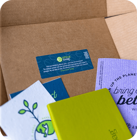 An open cardboard box filled with various branded merchandise like notebooks, a t-shirt, and stickers, representing achieving brand goals.