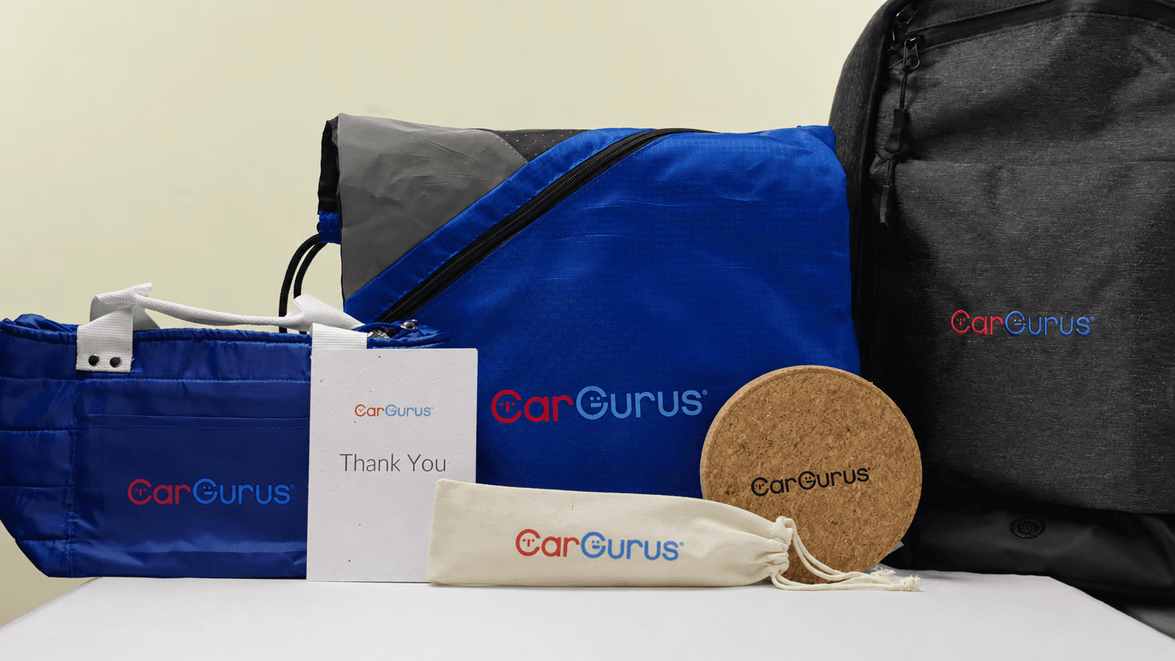 CarGurus-branded gift items: duffel bag, backpack, drawstring pouch, coaster, and thank you card
