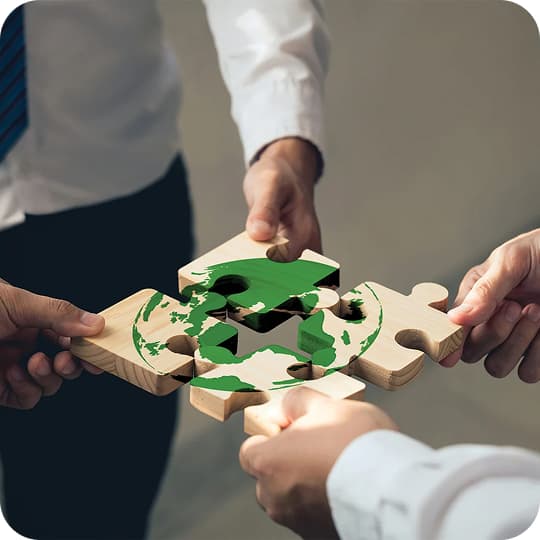 Collaborative hands assembling a wooden puzzle of the Earth, symbolizing teamwork and global responsibility.